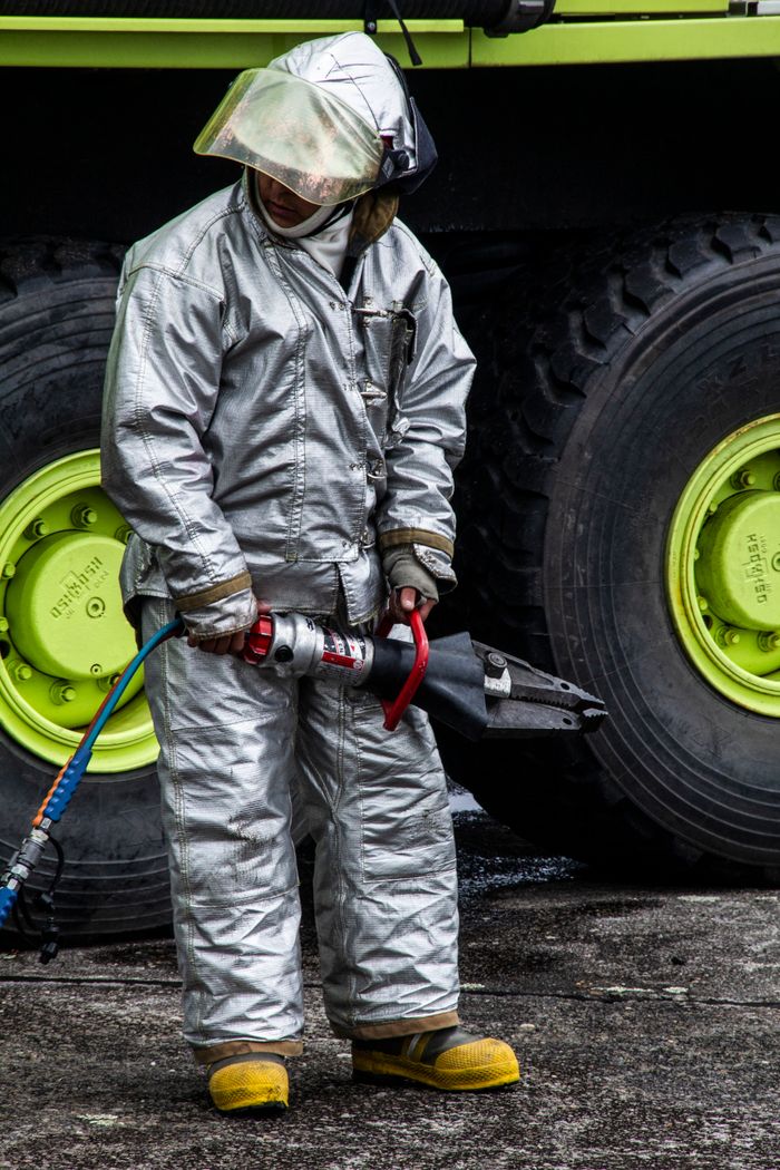 Firefighter in reflective protective gear using rescue equipment outdoors.