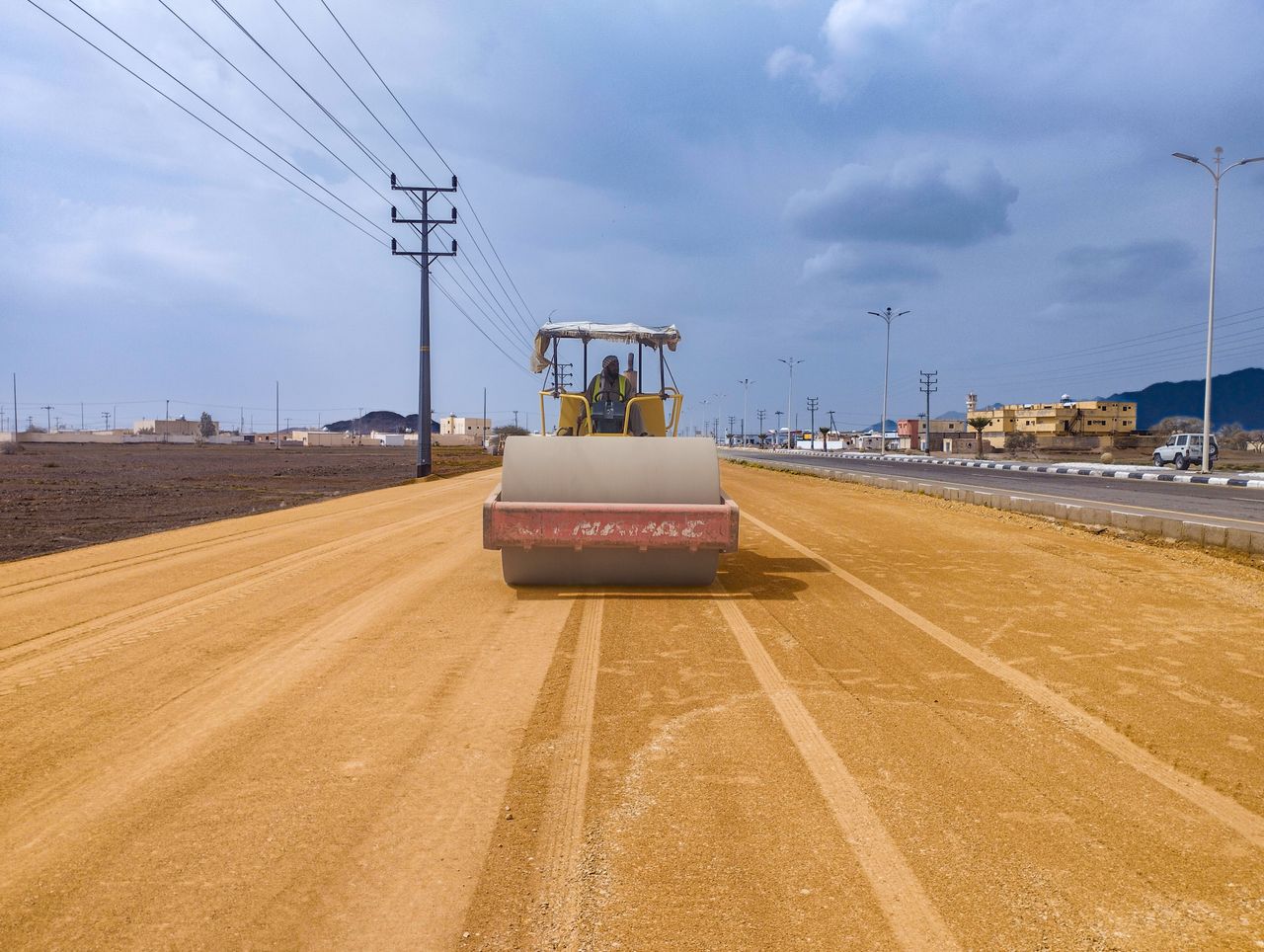 Road roller compacting dirt on highway construction in Saudi Arabia.